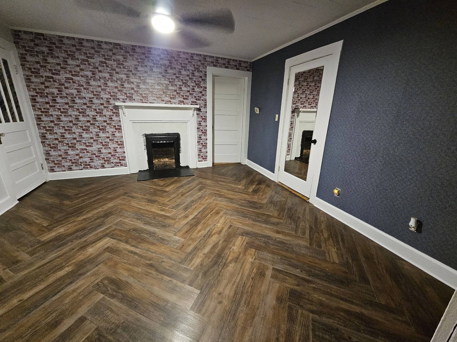 Finished room with fireplace and dark walnut herringbone LVP floor